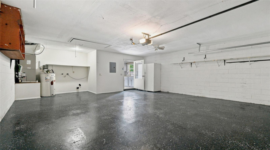 Spacious Garage With Textured Flooring, White Painted Block Walls, And A Utility Area Featuring A Water Heater