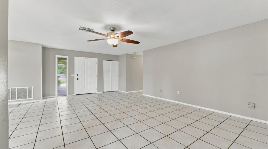 Tiled Flooring Throughout, Ceiling Fan With Integrated Lighting, White Paneled Entry Door, And Bi-Fold Closet Doors