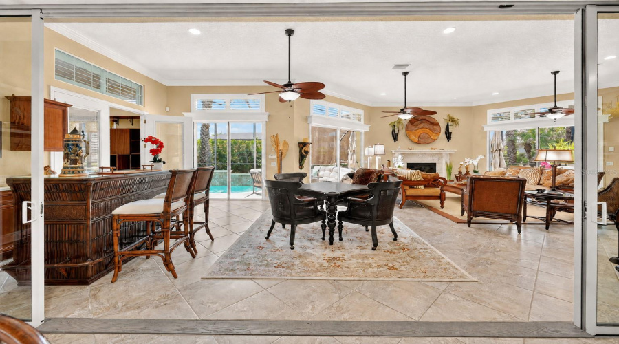 Entrance To Gathering Room Via Stack Back Sliding Glass Doors - Wide Angle View Shows (L To R): Wet Bar W/ Bar Height Chairs Just Beyond L Slider; French Doors To Br #4; 2 Sets Of Sliding Glass Doors W/ Overhead Transoms That Open To The Pool Area (L Back); Fireplace W/ Cut Coral Surround &Amp; Mantle (Center Back); And Sliding Glass Doors That Open To Custom Built-In Spa Area (Back R).