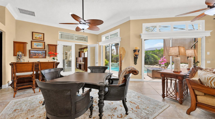 Close-Up View Of South End Of The Gathering Room: Wet Bar (Far L); French Doors W/ Built-In Blinds Lead To Br #4 &Amp; Ba #3/Pool Bath (Center L); And Pool Area Visible Through 2 Sets Of Sliding Glass Doors W/ Overhead Transom Windows (R Back). Note The Black Kahala Club Game Table W/ 4 Black Caned-Back Swivel Game Chairs From The Royal Kahala Collection Manufactured By Tommy Bahama Home.