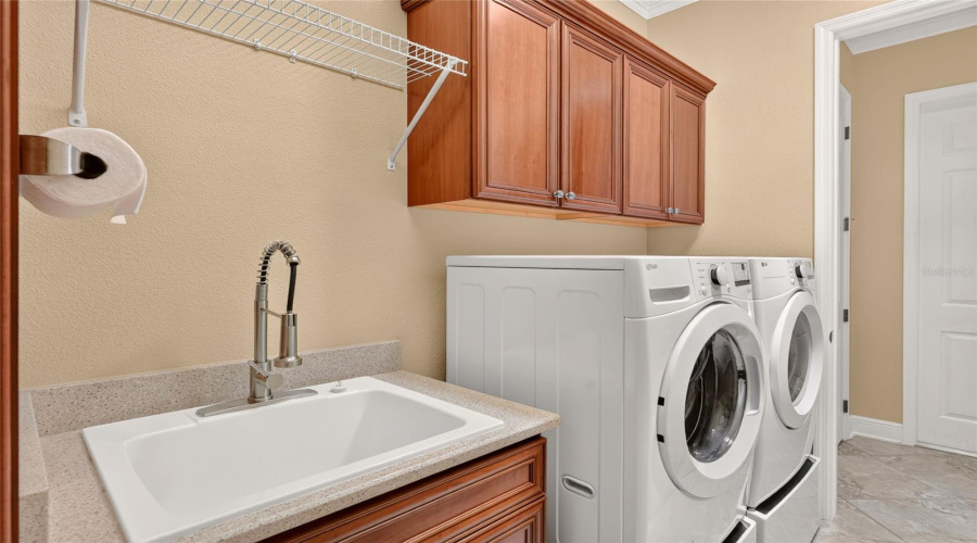 Close-Up View Of Interior Laundry - Note Cabinet Storage Above Front Load Washer &Amp;Dryer And Laundry Sink With Wood Vanity, Quartz Countertop, And Pull Down Faucet.