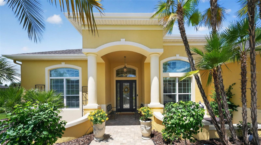 A Covered Front Porch W/ White Columns &Amp; Curved Stucco Half Walls Leads To A Freshly Painted, Black Entry Door W/ Full-Length Leaded-Glass Insert, Matching Sidelights And An Arched Transom.