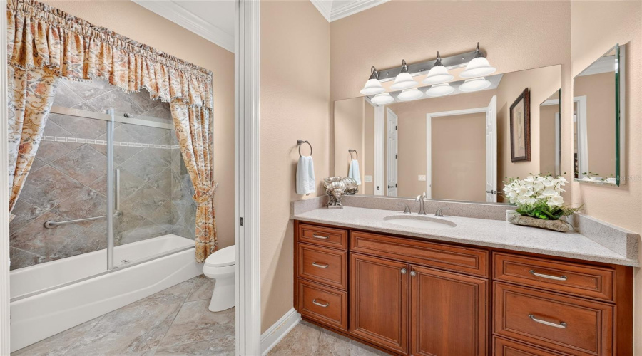 Bathroom #2 - Located Between Br #3 (Front) And Br #2 (Back Bedroom On Guest Hallway). View Shows Single Vanity W/ Quartz  Countertop W/ Undermount Sink. Pocket Door Provides Private Area To Tub/Shower Combo And Comfort Height Toilet. Linen Closet Is Partially Visible In Mirror Reflection.