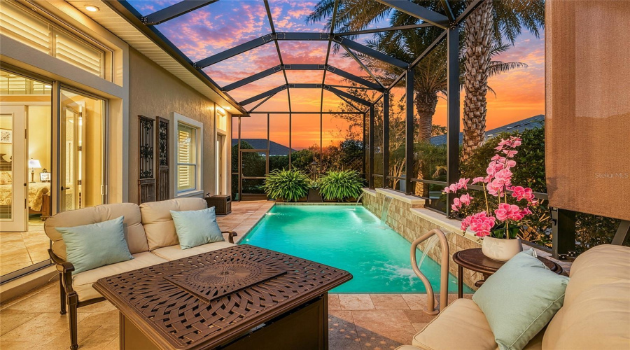 Pool Area Under Mansard Screen Enclosure During Twillght - What An Enchanting Place To Experience In Your Own Tropical Backyard! The 3 Cascading Waterfalls Of The Pool Seem To Come Alive W/ Relaxing Water Movement Sounds And The Pool Lights Change Colors As If Dancing To Its Own Music. Note Fire Pit Located Between The Outdoor Sofa &Amp; Love Seat.