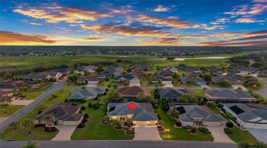 Aerial – Looking West – A Vivid Sunset Settles Over The Neighborhood, Creating A Distinct Evening Perspective Across The Homes And Nearby Golf Landscape. Virtually Enhanced.