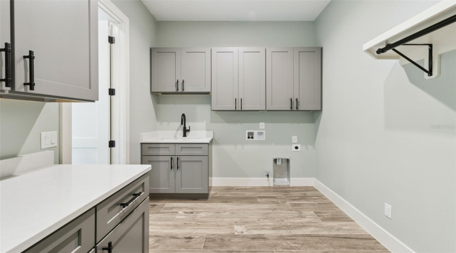 Laundry Room With Built-In Cabinetry And Utility Sink