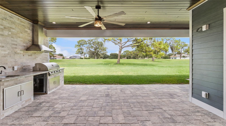 Covered Outdoor Kitchen With Built-In Grill And Entertaining Space
