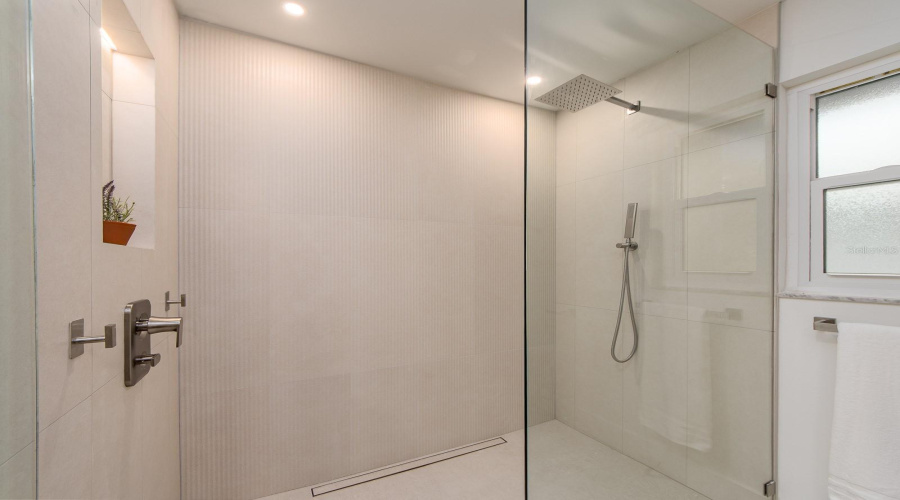 Shower Features A Frameless Glass Enclosure And Lighted Niche