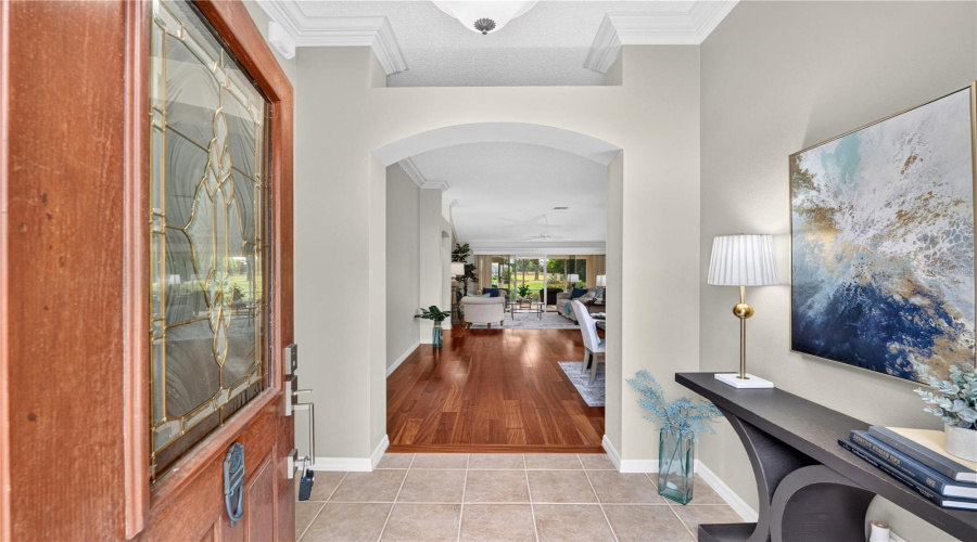 Spacious Foyer With Rich Wood Flooring, Neutral Tones, And A Graceful Arched Opening Leading Into The Main Living Areas.