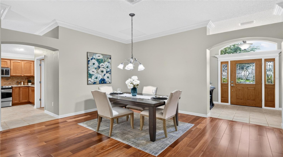 Formal Dining Space Positioned Near The Front Entry, Featuring Pendant Lighting, Neutral Finishes, And Access To The Kitchen.