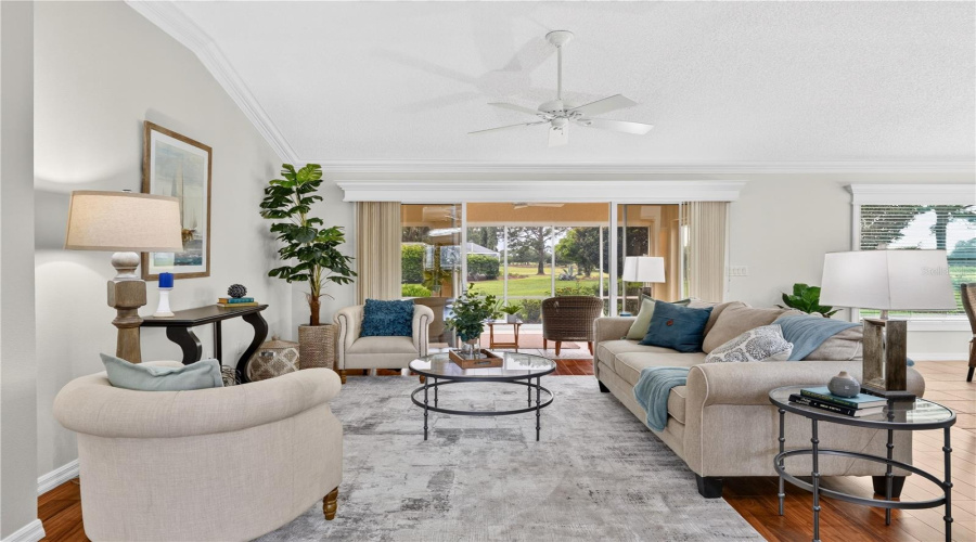 Light-Filled Living Room With Comfortable Gathering Space, High Ceilings, And Large Windows Overlooking The Outdoor Views.