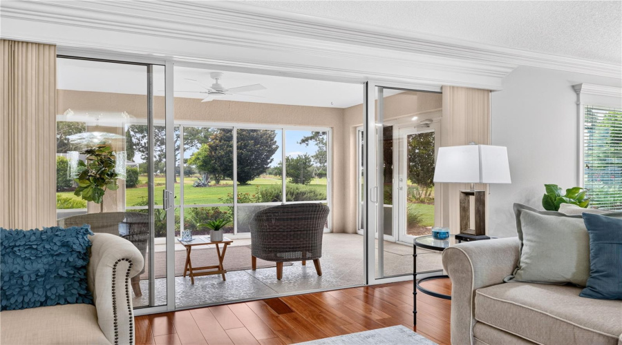 Living Area With Sliding Glass Doors Opening To The Enclosed Lanai And Peaceful Green Views Beyond.