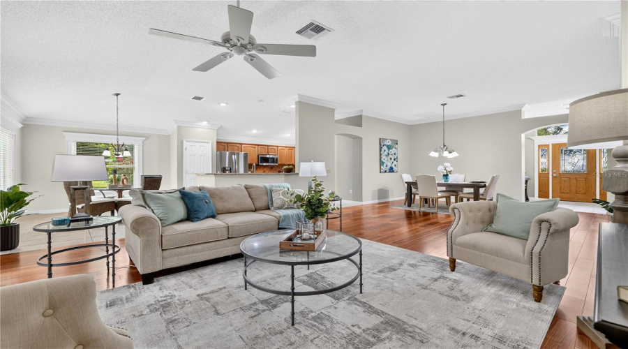 Open Living Room With High Ceilings, Neutral Finishes, And A Comfortable Layout That Flows Easily Into The Dining And Kitchen Areas