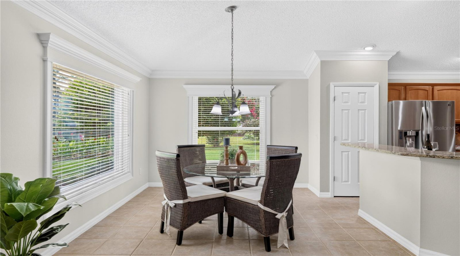 Charming Breakfast Nook With Large Windows, Soft Natural Light, And Peaceful Views Of The Surrounding Green Space.