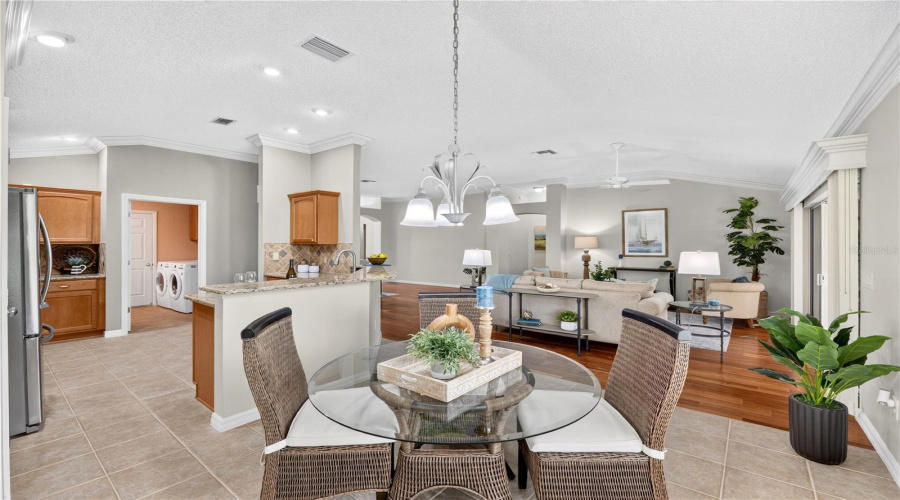 Bright Breakfast Nook With Large Windows, Pendant Lighting, And An Open Flow To The Kitchen And Living Room.