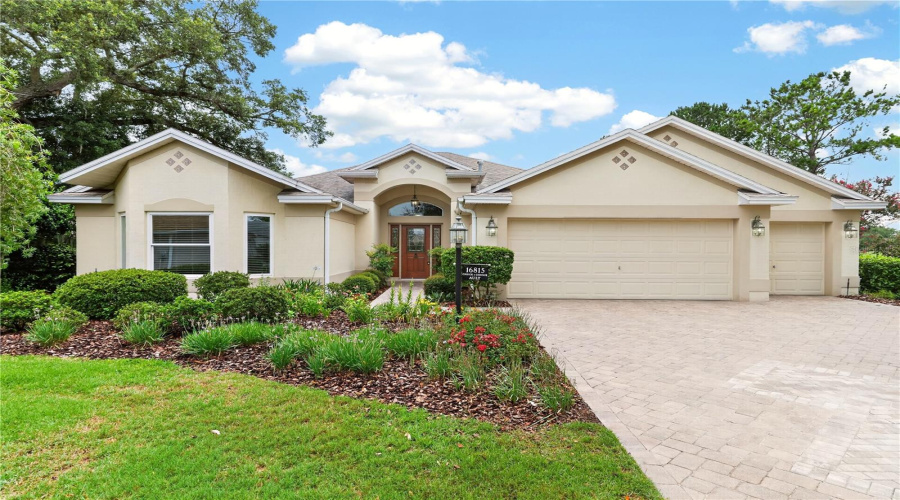 Welcoming Front Exterior With A Spacious Driveway, Two-Car Garage, Arched Entryway, And Well-Maintained Landscaping.