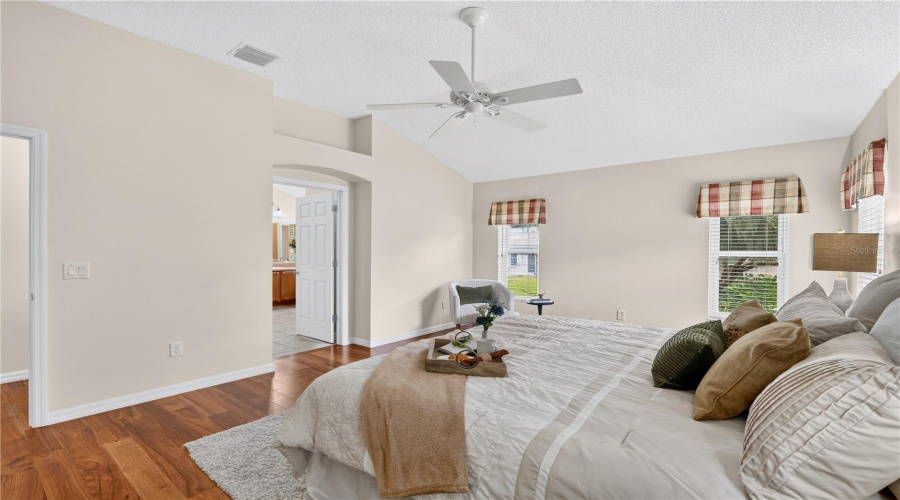 Primary Suite View Highlighting The Generous Room Size, Neutral Finishes, And Private Access Toward The En-Suite Bath.