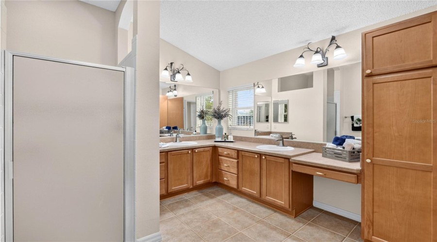 Primary Bathroom View Showcasing Dual Vanities, Wood Cabinetry, Generous Counter Space, And A Bright, Spacious Layout.