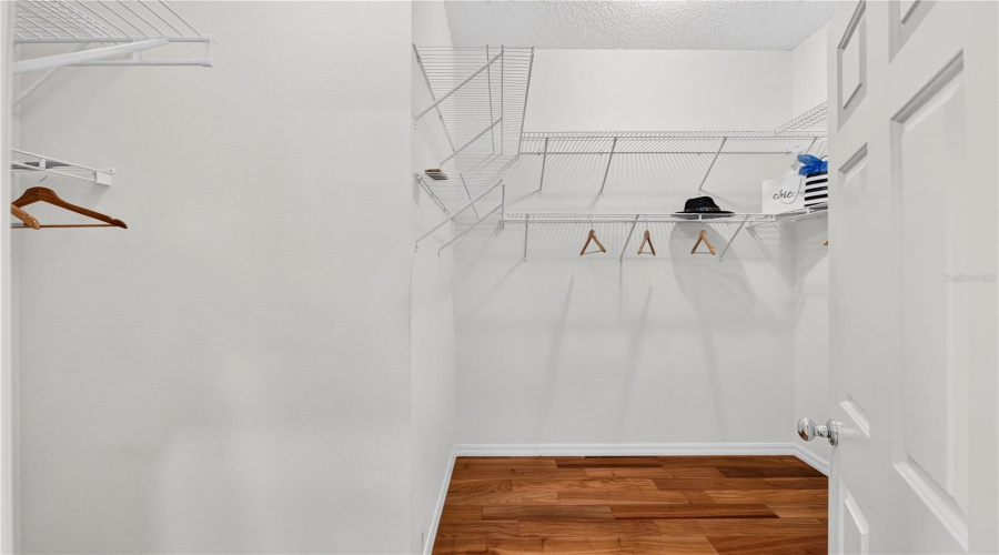 Large Walk-In Closet With Wood Flooring, Wire Shelving, And Excellent Storage Capacity.