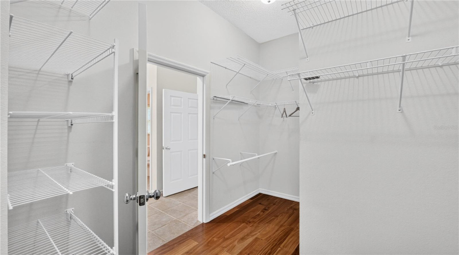 Spacious Walk-In Closet With Built-In Shelving And Hanging Space, Offering Practical Organization And Storage.
