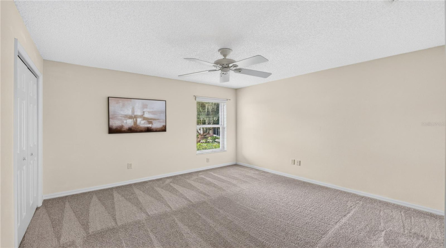 Additional Guest Bedroom With Soft Brand New Neutral Carpeting, Ceiling Fan, Closet Storage, And Natural Light.
