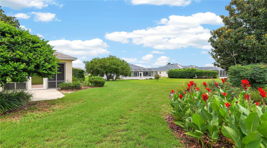 Spacious Backyard Setting With Lush Green Lawn, Colorful Landscaping, And Peaceful Open Views.