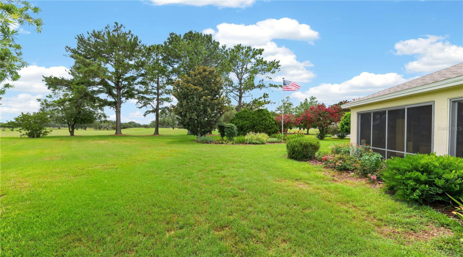 Rear Lawn And Garden View Showcasing The Home’s Peaceful Setting, Mature Trees, And Scenic Green Space.