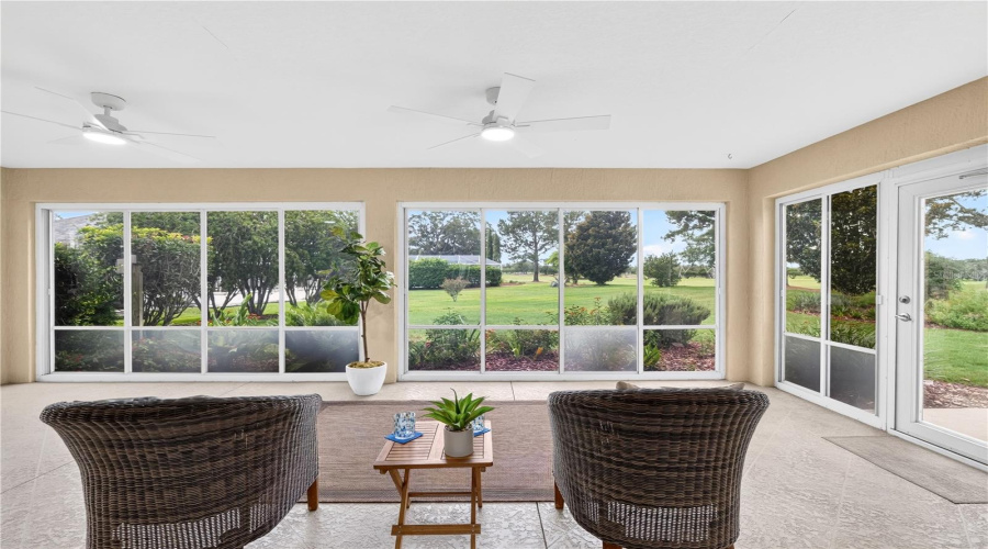 Enclosed Lanai With Expansive Windows, Ceiling Fan, And Beautiful Views Of The Green Space And Mature Landscaping.