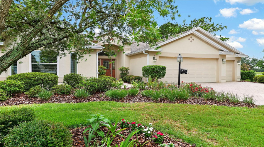 Charming Front Exterior Framed By Colorful Landscaping, Mature Trees, And A Beautifully Maintained Lawn.