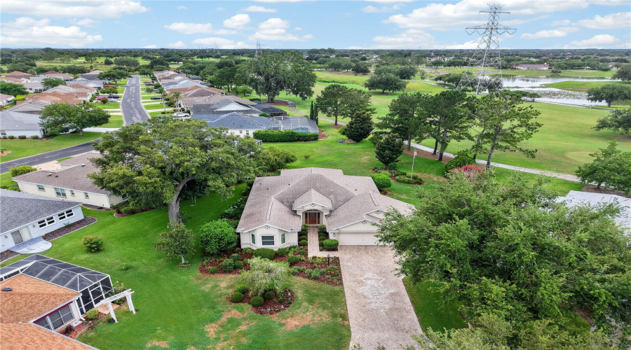Aerial View Showcasing The Home’s Beautiful Setting, Mature Trees, Long Driveway, And Nearby Golf Course Views.