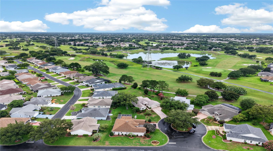 Expansive Aerial Perspective Highlighting The The Cul-De-Sac, Surrounding Neighborhood, Green Space, Golf Course Setting, And Scenic Water Views Nearby
