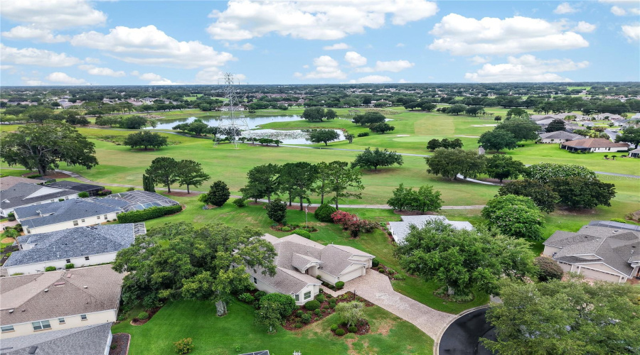 Expansive Aerial View Showcasing The Home’s Scenic Golf Course Setting, Surrounding Green Space, Mature Trees, And Nearby Water Views.