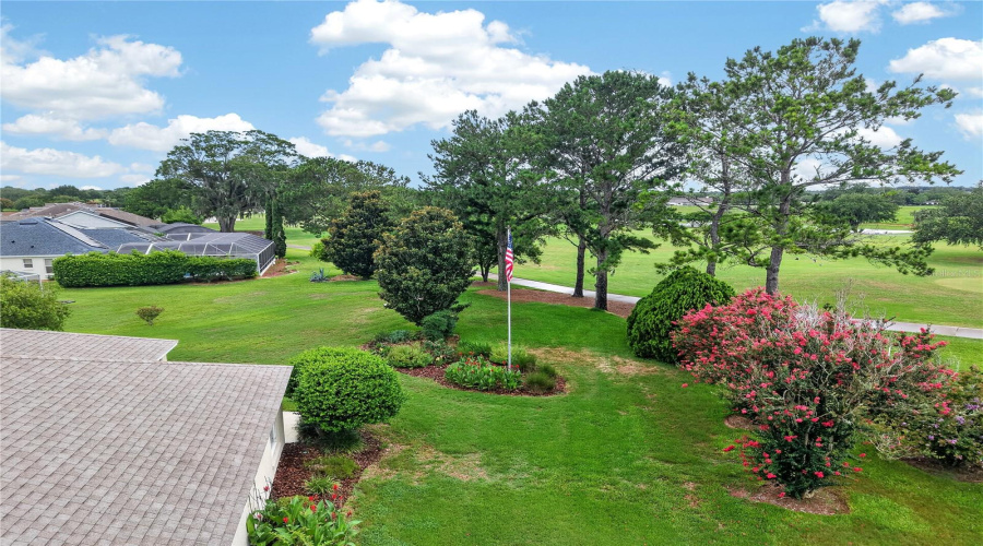 Aerial View Highlighting The Beautiful Rear Lawn, Mature Landscaping, And Peaceful Golf Course Backdrop.