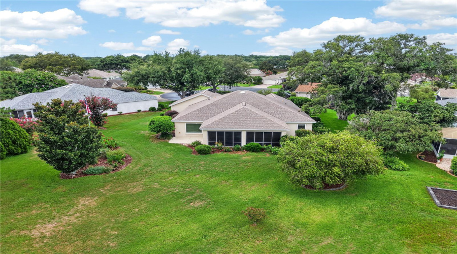 Rear Aerial View Showcasing The Enclosed Lanai, Spacious Lawn, Mature Trees, And Private-Feeling Outdoor Setting.