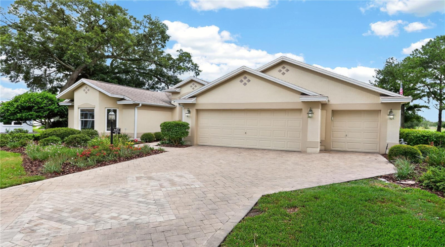 Front Exterior View With Broad Driveway, Two-Car Garage Plus Golf Cart Garage, Mature Landscaping, And Attractive Curb Appeal.