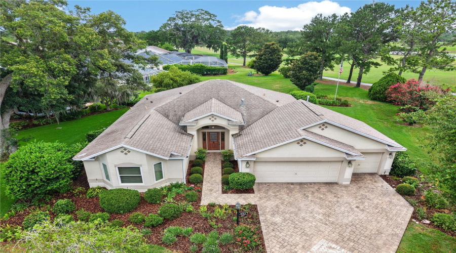 Beautiful Aerial View Showcasing The Home’s Attractive Roofline, Mature Landscaping, And Peaceful Setting With Golf Course Views Beyond.