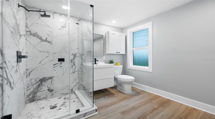 Bathroom With Glass Enclosed Shower And Convenient Laundry.