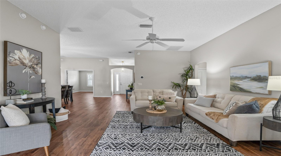 Another View Of The Main Living Area Highlights The Open Floor Plan, Vaulted Ceiling, And Seamless Connection Between The Living Room, Dining Area, Kitchen, And Lanai.