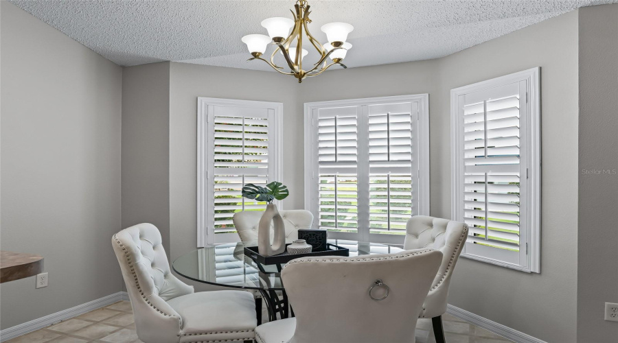 Charming Breakfast Nook Surrounded By Plantation-Shuttered Windows, Creating A Bright And Inviting Spot For Morning Coffee Or Casual Meals.