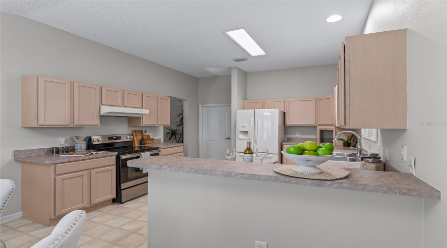 Spacious Kitchen With Abundant Cabinetry, Generous Counter Space, Recessed Lighting, And A Convenient Breakfast Bar Overlooking The Dining Nook. Gas Is Available Behind The Range For Buyers Who Prefer Gas Cooking.