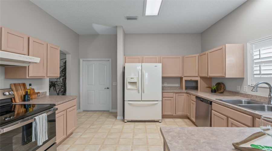 Functional Kitchen Layout With Ample Cabinet And Counter Space, French-Door Refrigerator, Pantry Access, And Easy Flow To The Adjoining Breakfast Nook.