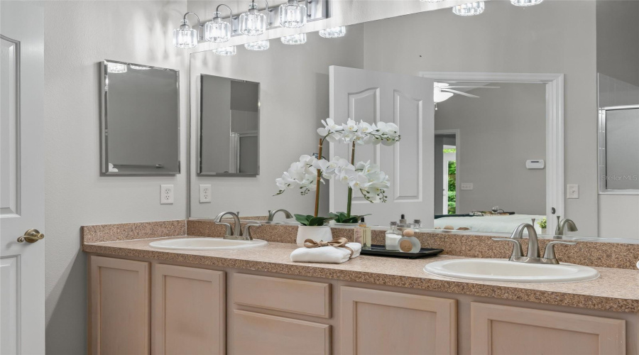 Dual-Sink Vanity Provides Plenty Of Counter Space For Two, Complemented By Updated Light Fixtures And Abundant Cabinetry Below.