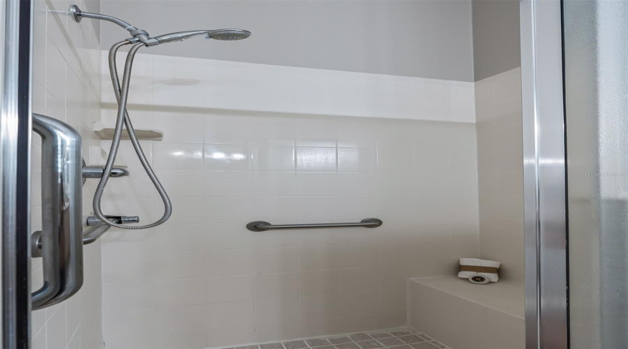 Close-Up Of The Primary Bath’s Walk-In Shower With Built-In Grab Bar And Handheld Shower Feature For Added Functionality.