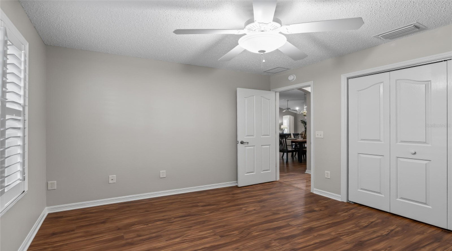 Another View Of The Guest Bedroom Highlights The Closet Storage, Natural Light, And Warm Wood-Look Lvp Flooring.