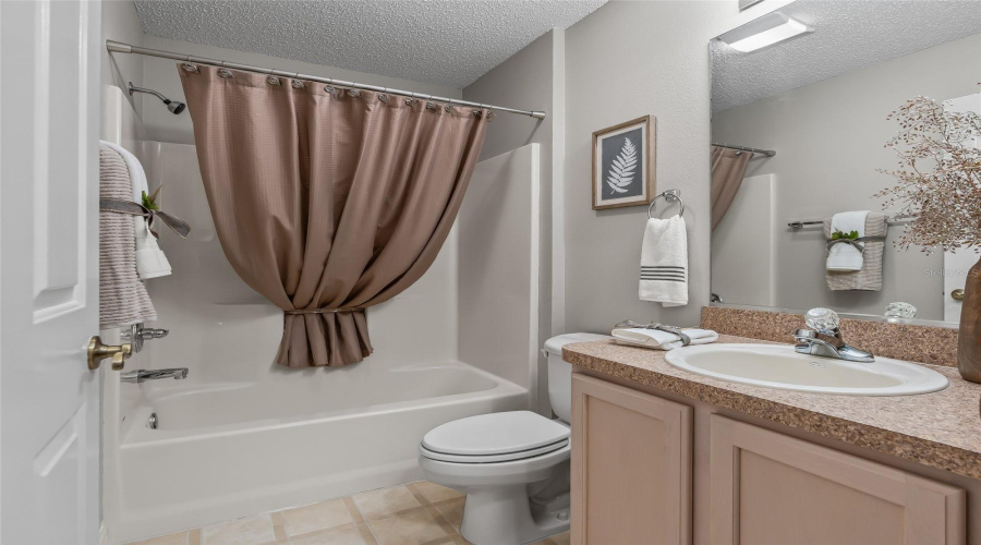 Convenient Guest Bathroom With Tub/Shower Combination, Vanity Storage, And Neutral Finishes—Perfectly Positioned For Visitors.