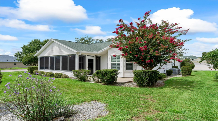 Beautiful Backyard Setting With Mature Landscaping, Flowering Trees, And A Spacious Lawn Surrounding The Enclosed Lanai.