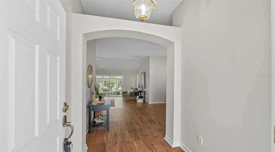 Step Inside To A Bright, Welcoming Entry With An Arched Opening Leading Into The Main Living Areas And Warm Wood-Look Lvp Flooring Beyond.