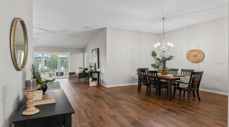 Open Living And Dining Area Featuring Newer Wood-Look Lvp Flooring, Abundant Natural Light, And An Easy Flow Toward The Enclosed Lanai—Ideal For Everyday Living And Entertaining.