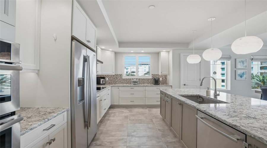 Bright Kitchen With Stone Countertops And Generous Cabinetry.