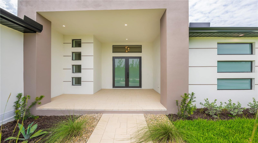 Grand Covered Entry With Soaring Ceilings And Custom Double Doors.